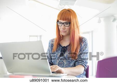 Businesswoman working on laptop in creative office View Large Photo Image Stock Image - Businesswoman working on laptop in creative office. Fotosearch