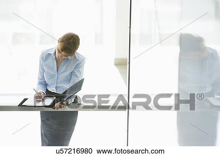 Businesswoman writing on document in office View Large Photo Image Stock Image - Businesswoman writing on document in office. Fotosearch