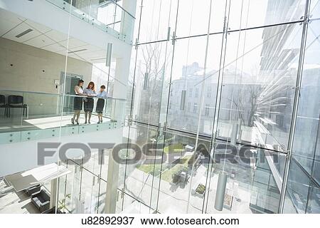 Businesswomen discussing at office balcony View Large Photo Image Stock Photo - Businesswomen discussing at office balcony. Fotosearch