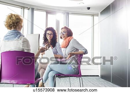 Businesswomen discussing in creative office View Large Photo Image Stock Photo - Businesswomen discussing in creative office. Fotosearch
