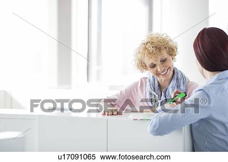 Stock Photography - Businesswomen discussing in creative office. Fotosearch
