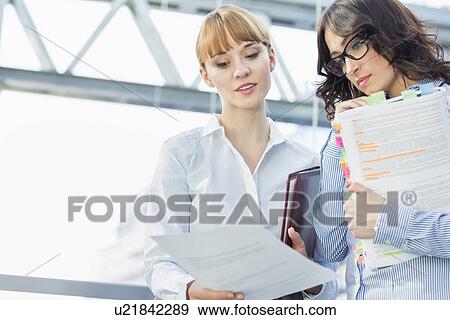 Stock Photo - Businesswomen reading document in office. Fotosearch