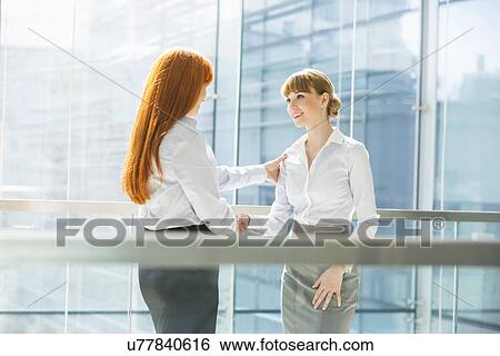 Stock Photograph - Businesswomen shaking hands in office. Fotosearch