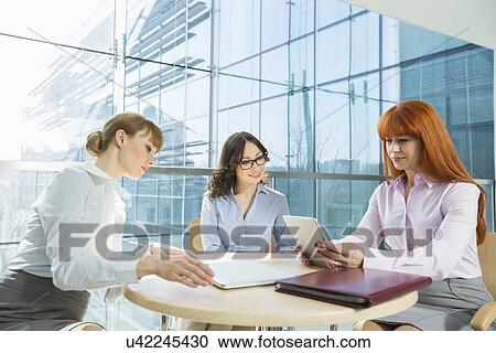 Stock Image - Businesswomen using digital tablet in office. Fotosearch