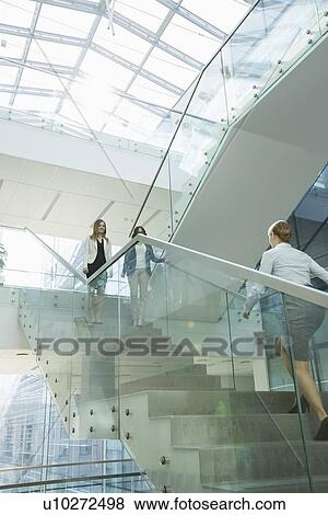 Stock Photo - Businesswomen walking on steps in office. Fotosearch