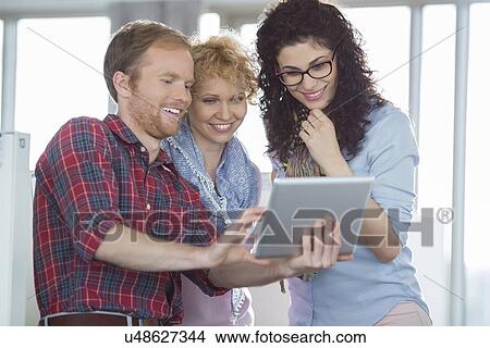 Businesswomen with male colleague using tablet PC in creative office View Large Photo Image Picture - Businesswomen with male colleague using tablet PC in creative office. Fotosearch