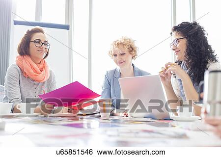 Businesswomen working at desk in creative office View Large Photo Image Stock Photograph - Businesswomen working at desk in creative office. Fotosearch