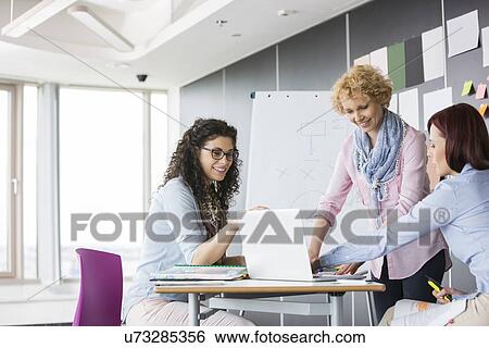 Stock Photograph - Businesswomen working together in creative office. Fotosearch
