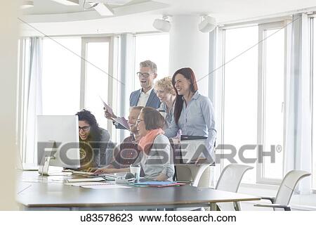 Stock Image - Cheerful businesspeople working together at conference table. Fotosearch