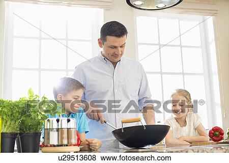 Children looking at father preparing food in kitchen View Large Photo Image Stock Photo - Children looking at father preparing food in kitchen. Fotosearch
