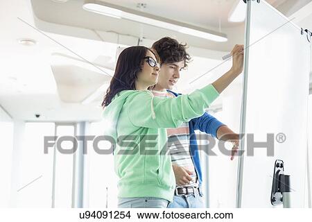 Picture - Colleagues preparing presentation on whiteboard in creative office. Fotosearch