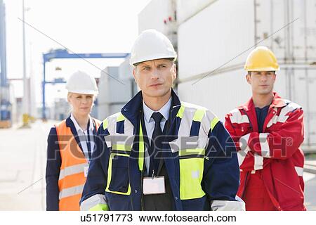 Stock Image - Confident workers standing in shipping yard. Fotosearch