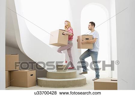 Couple carrying cardboard boxes up stairs in new house View Large Photo Image Stock Photo - Couple carrying cardboard boxes up stairs in new house. Fotosearch