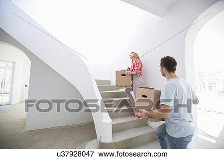 Couple carrying moving boxes up stairs in new house View Large Photo Image Stock Photo - Couple carrying moving boxes up stairs in new house. Fotosearch