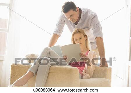 Couple reading magazine together at home View Large Photo Image Picture - Couple reading magazine together at home. Fotosearch