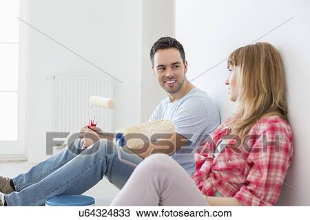 Couple taking break from painting in new home View Large Photo Image Stock Image - Couple taking break from painting in new home. Fotosearch
