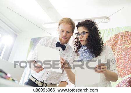 Stock Photograph - Creative business colleagues discussing over samples in office. Fotosearch