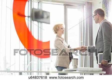 Creative business colleagues shaking hands in office View Large Photo Image Stock Photo - Creative business colleagues shaking hands in office. Fotosearch