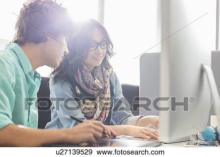 Creative business colleagues using desktop computer in office View Large Photo Image Stock Photo - Creative business colleagues using desktop computer in office. Fotosearch