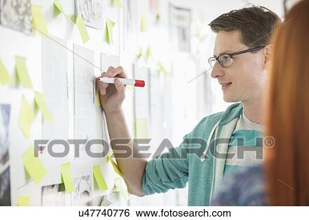 Stock Photograph - Creative businessman writing notes on paper in office. Fotosearch