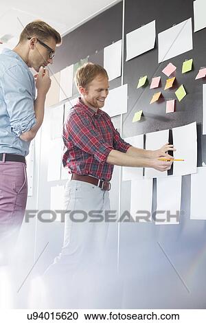 Creative businessmen discussing over document on wall in office View Large Photo Image Stock Image - Creative businessmen discussing over document on wall in office. Fotosearch