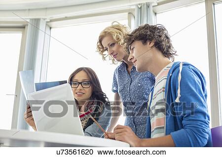 Stock Image - Creative businesspeople working in office. Fotosearch