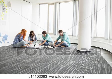 Creative businesspeople working on floor in office View Large Photo Image Stock Image - Creative businesspeople working on floor in office. Fotosearch