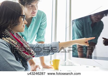 Creative businesswoman showing something to colleague on desktop computer in office View Large Photo Image Stock Photo - Creative businesswoman showing something to colleague on desktop computer in office. Fotosearch