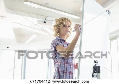 Creative businesswoman writing on presentation board in office View Large Photo Image Stock Image - Creative businesswoman writing on presentation board in office. Fotosearch