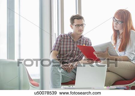 Creative colleagues reading file in office View Large Photo Image Stock Photo - Creative colleagues reading file in office. Fotosearch