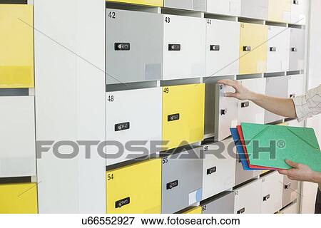 Stock Photo - Cropped image of businessman putting files in locker at creative office. Fotosearch