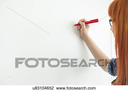 Stock Image - Cropped image of businesswomen writing on whiteboard in creative office. Fotosearch
