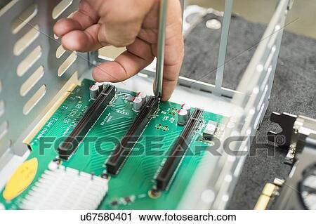 Stock Image - Cropped image of male technician repairing PCI slots in computer factory. Fotosearch