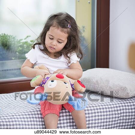 Stock Photo - Cute girl playing toy guitar at home. Fotosearch