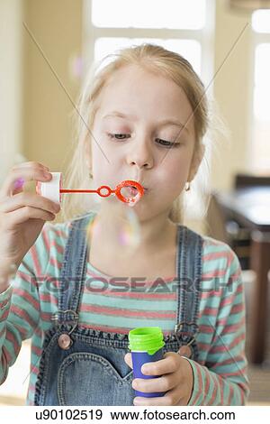 Cute girl playing with bubble wand at home View Large Photo Image Stock Photo - Cute girl playing with bubble wand at home. Fotosearch