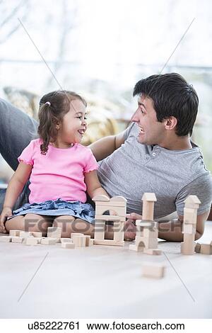 Cute girl teasing father while playing with wooden building blocks at home View Large Photo Image Stock Image - Cute girl teasing father while playing with wooden building blocks at home. Fotosearch
