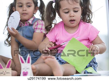 Stock Photo - Cute girls with craft papers at home. Fotosearch