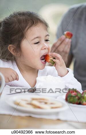 Cute little girl eating strawberry with father at breakfast table View Large Photo Image Stock Photograph - Cute little girl eating strawberry with father at breakfast table. Fotosearch