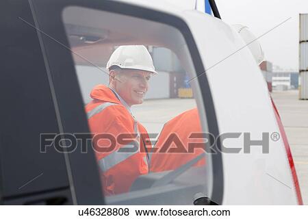Stock Photo - Engineers conversing beside car in shipping yard. Fotosearch