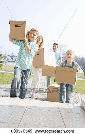 Stock Photo - Family carrying cardboard boxes while entering new house. Fotosearch