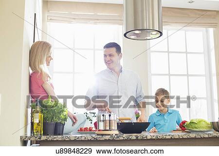 Family preparing food in kitchen View Large Photo Image Stock Photo - Family preparing food in kitchen. Fotosearch