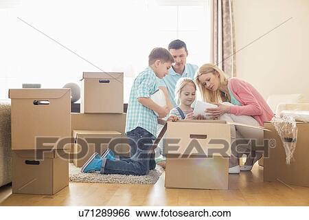 Family unpacking cardboard boxes at new home View Large Photo Image Stock Photograph - Family unpacking cardboard boxes at new home. Fotosearch