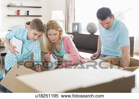 Stock Photography - Family unpacking cardboard boxes in new house. Fotosearch