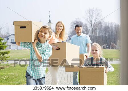 Family with cardboard boxes moving into new house View Large Photo Image Picture - Family with cardboard boxes moving into new house. Fotosearch