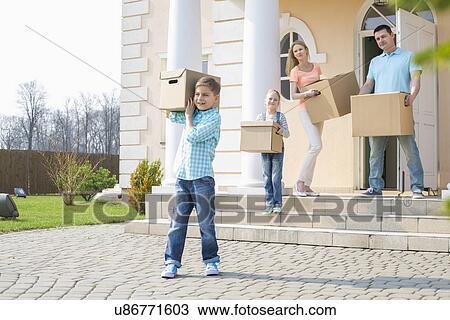 Stock Image - Family with cardboard boxes moving out from house. Fotosearch