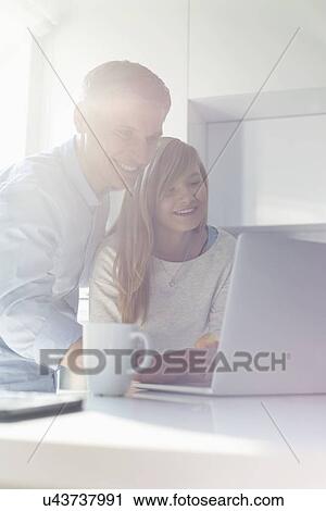 Stock Image - Father and daughter using laptop at home. Fotosearch