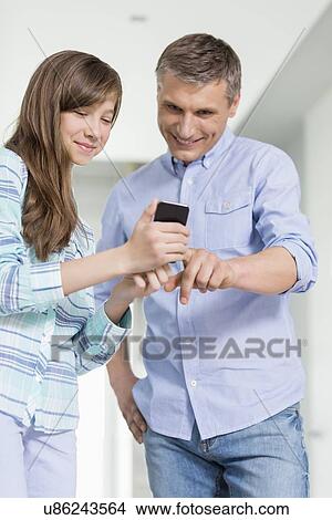 Father and daughter using smart phone at home View Large Photo Image Picture - Father and daughter using smart phone at home. Fotosearch