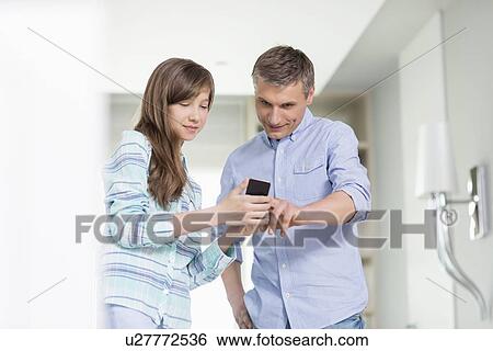 Father and daughter using smart phone at home View Large Photo Image Stock Photograph - Father and daughter using smart phone at home. Fotosearch