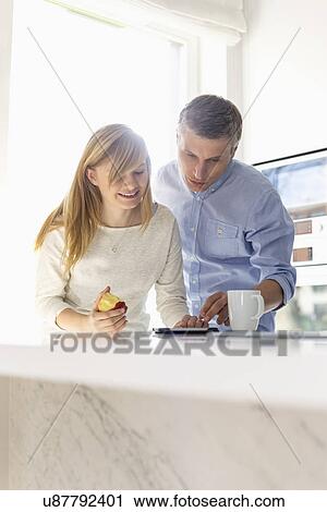 Stock Image - Father and daughter using tablet PC at home. Fotosearch