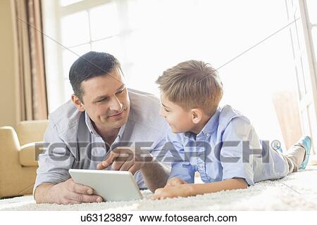 Father and son using digital table on floor at home View Large Photo Image Stock Photo - Father and son using digital table on floor at home. Fotosearch